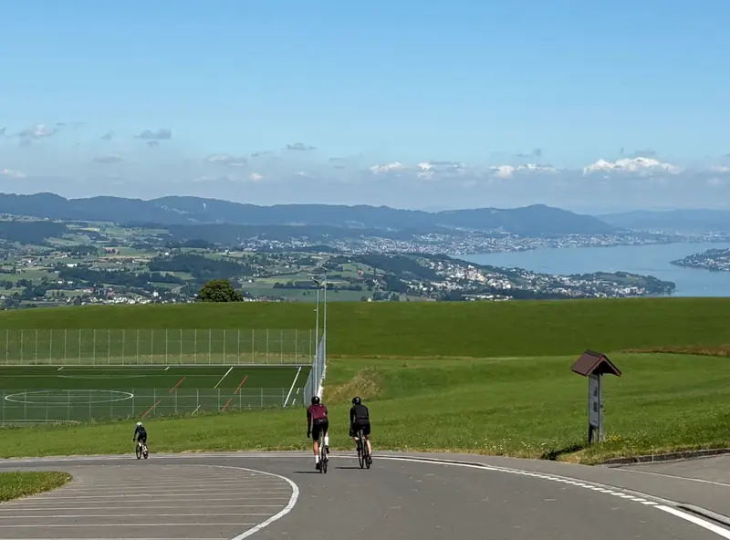 Road cyclists riding fast along quiet lanes above Lake Zurich with the Alps in the distance